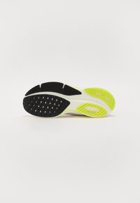 Suela de zapato con una base de goma negra, acentos amarillos y un diseño texturizado. Presenta lugs triangulares para tracción y una construcción duradera.