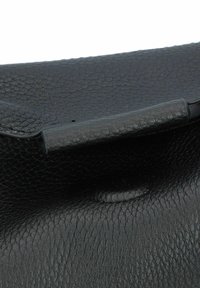 Schwarze Lederhandtasche mit strukturiertem Finish, ausgestattet mit einem glatten, gerollten Griff und einem subtilen Knopfdetail auf dem Vorderklappen.