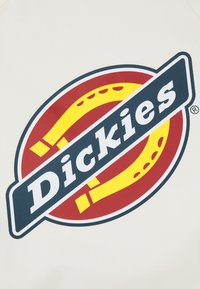 Bela podlaga z večjim krogom logotipa. Rdeča in rumena barva z temno modrim trakom, ki prikazuje besedo "Dickies" v debelih, belih črkah.