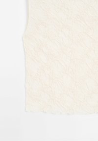 Tissu blanc sans manches avec un motif floral texturé et de légers plis, présenté sur un fond blanc uni.