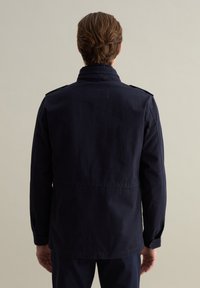 Marineblaue Baumwolljacke mit hohem Kragen, Schulterklappen und gerader Schnittführung. Verfügt über lange Ärmel und sichtbare Nähte.
