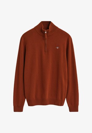 Brun pullovertröja med hög krage, dragkedja och ribbade muddarna. Mjuk tyg med en diskret logotypdetalj på bröstet.