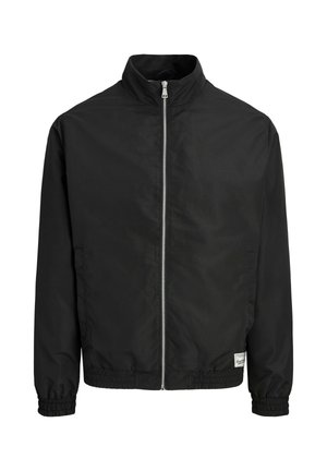 Must kerge jope eesrihmaga, kõrge krae, elastsete varrukaotste ja äärega ning väike valge ristkülikukujuline silt ääre lähedal.