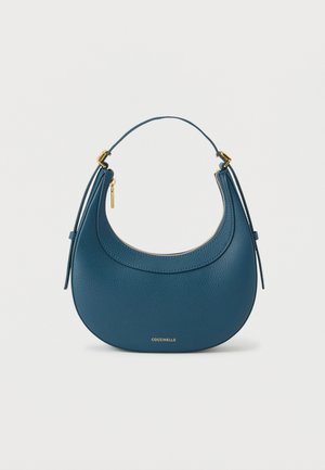 Niebieska skórzana torebka o zakrzywionym kształcie, z złotymi akcentami, zamkiem błyskawicznym i krótkim uchwytem ułatwiającym przenoszenie.