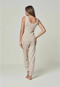 Beige gerippter Tanktop mit rundem Rückenausschnitt, kombiniert mit passenden, tapered Hosen mit elastischen Bündchen. Weiches Material und taillierte Passform.
