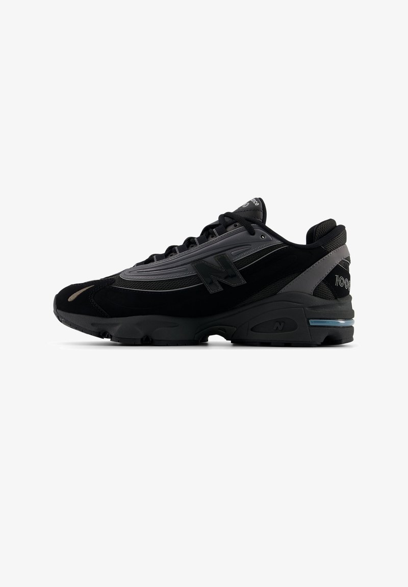 Baskets de sport noires et grises avec dessus en mesh et synthétique, fermeture à lacets, semelle amortissante et logos de la marque sur le côté et le talon.