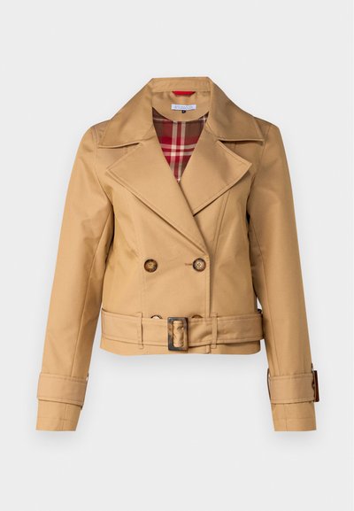 Tan double-breasted jacket with wide lapels, belted waist, button accents, and a plaid lining visible at the collar. Smooth fabric texture.
