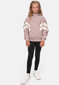 Lyserød hættebomberjakke med hvide, vinklede striber på ærmerne, parret med sorte leggings og hvide sneakers. Glat, nylon tekstur.