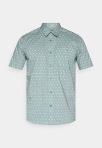 Κοντομάνικο πουκάμισο από ανοιχτό μπλε ύφασμα με λευκές βούλες, γιακά με κουμπιά και τσέπη στο στήθος με μικρό λογότυπο.