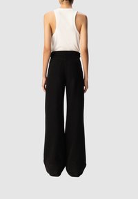 Pantaloni neri a gamba larga con vita alta, dotati di due tasche posteriori e una texture del tessuto liscia. Design semplice, senza motivi visibili.