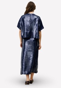 Marineblauwe jurk met pailletten, bestaande uit een cropped top, een lange rok en korte mouwen, met een gladde textuur en glanzend oppervlak.