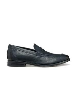 Mocasines de cuero azul marino con textura suave, diseño de slip-on, costuras decorativas y un bajo tacón apilado. Punta redondeada con acentos mínimos.