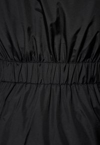 Černý elastický pas s nařasenou texturou, vyrobený z hladké, lesklé látky. Jednoduchý design s konzistentním, rovnoměrným šitím.