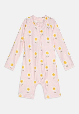 Rosa langermet romper med glidelås, prydet med gule smilende blomster med grønne stilker på en hvit prikkete bakgrunn.