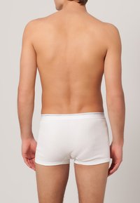 Witte katoenen boxershorts met een aansluitend ontwerp, elastische tailleband met een subtiel logo en een gladde textuur, weergegeven vanuit de achterkant.