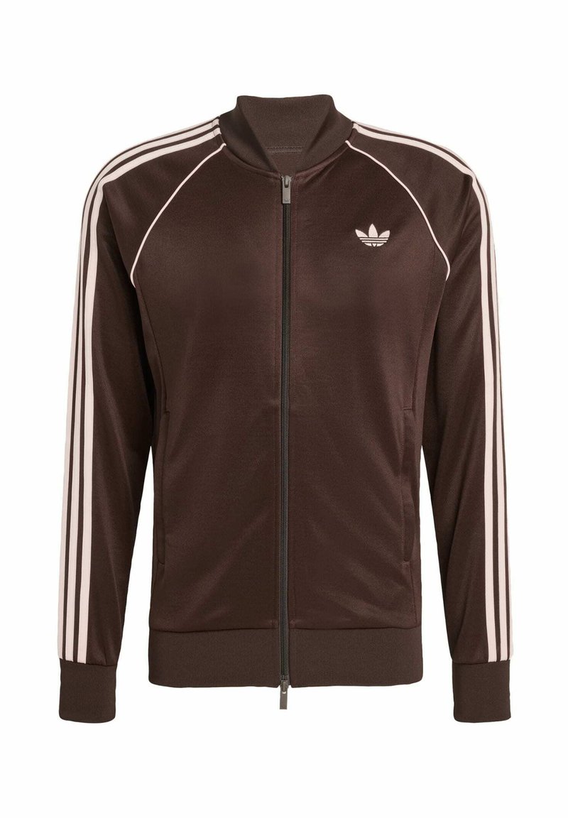 Brun zip-up jacka med vita randiga detaljer och en liten logotyp på bröstet. Tillverkad av ett glatt material med ribbade ärmslut.