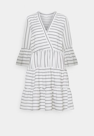 Robe blanche avec motifs de flèches noires, manches longues évasées, col en V et jupe à étages.