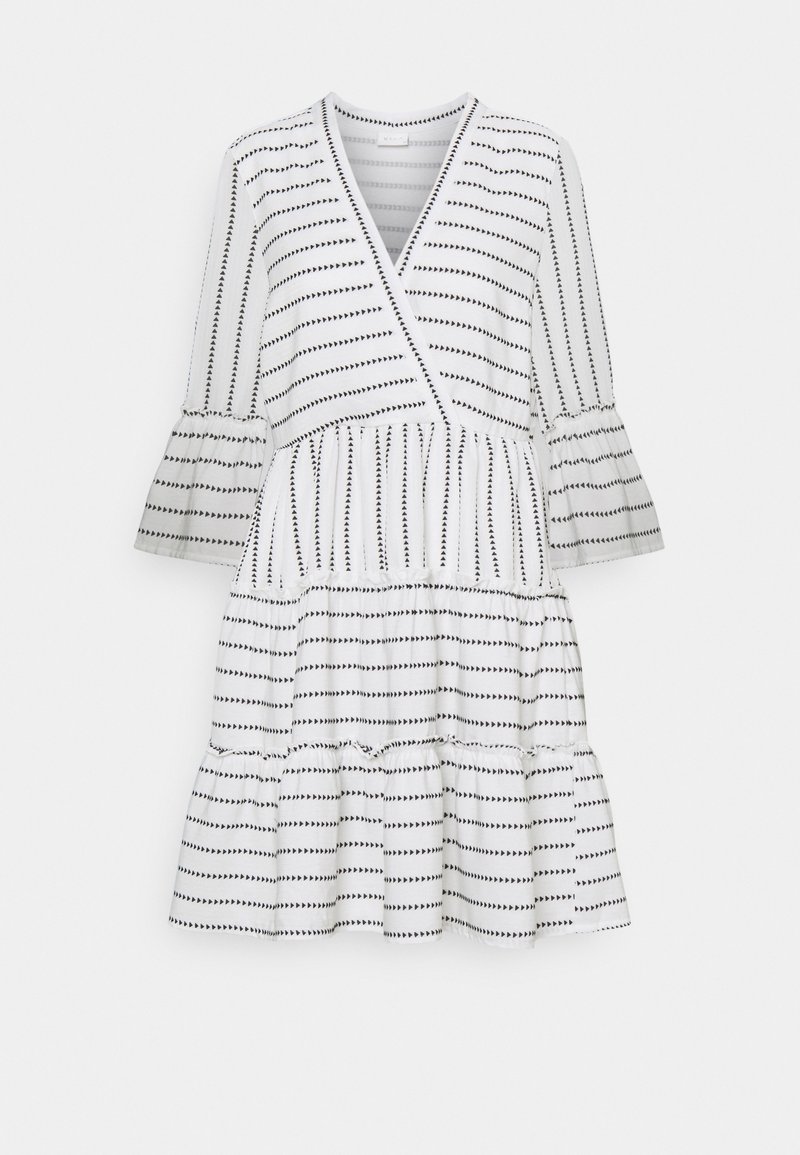 Robe blanche avec motifs de flèches noires, manches longues évasées, col en V et jupe à étages.
