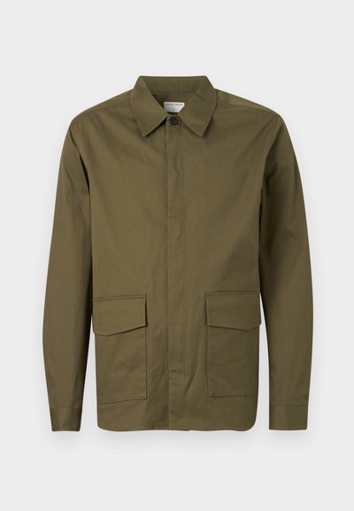 Μακριά μπουφάν σε ελιά πράσινο με γιακά σε σχήμα αιχμής, κλείσιμο με κουμπιά στο μπροστινό μέρος και δύο μεγάλα πλαϊνά τσέπες με καπάκι κοντά στον πάτο.