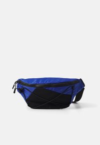 Blaue und schwarze Umhängetasche mit Reißverschluss, strukturiertem Stoff und diagonaler Panel-Design sowie verstellbarem Schultergurt.