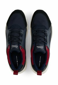 Sneaker Tommy Hilfiger navy, rossi e neri con suole bianche, lacci e logo sulla linguetta, visti dall'alto.