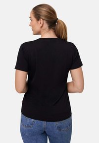 Sort kortærmet t-shirt, blødt stof, almindelig pasform, rund hals, ensfarvet design. Bæres med blå denim jeans med baglommer.