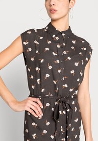 Abito camicia a fiori scuri con maniche corte, caratterizzato da una chiusura sul davanti con bottoni, colletto e vita legata. Decorato con motivi floreali bianchi e arancioni.