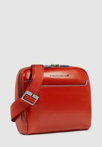 Rode leren schoudertas met een vlakke vorm, verstelbare band, zilverkleurige hardware en blauwe accentstiksels. Bovenaan ritssluiting.