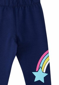 Marineblaue Leggings aus weichem Stoff, mit einem bunten Regenbogen und einem hellblauen Sternenmotiv auf dem unteren linken Bein. Elastischer Bund.