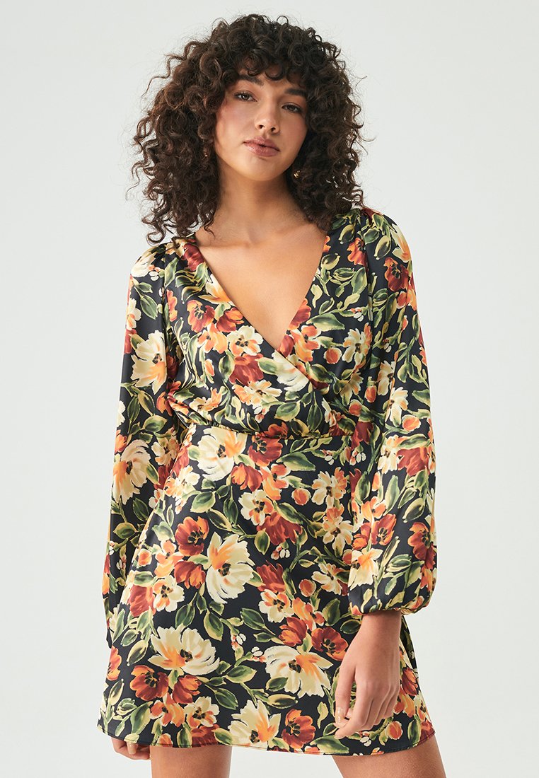 Robe enveloppante florale avec une base noire ornée de motifs botaniques orange, jaune et vert. Manches ballons longues et décolleté en V profond.