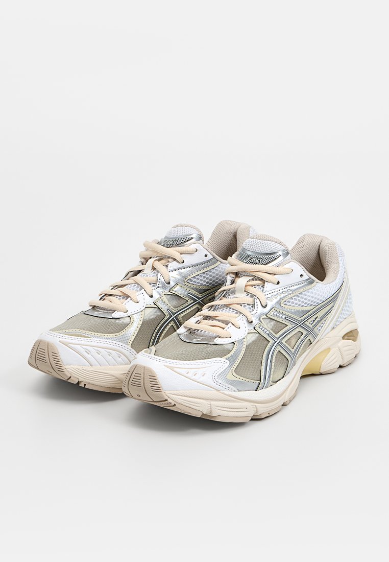 Witte en beige sport schoenen met een bovenwerk van mesh, metallic accenten en een dikke rubberen zool met textuurpatronen.