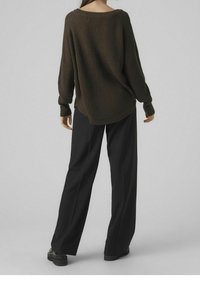 Maglione di maglia oversized verde scuro con un ampio scollo e polsini a coste, abbinato a pantaloni neri larghi e scarpe nere chunky.