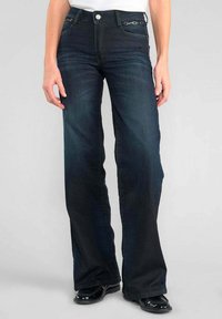 Jean évasé en denim bleu foncé avec un design classique à cinq poches, présentant des détails en métal argenté et une texture lisse.