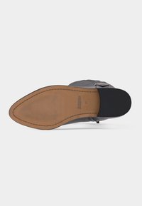 Semelle d'une botte en cuir noire taille 37 avec un bout pointu, un talon en caoutchouc, et une semelle en cuir beige texturée estampillée "BRONX".