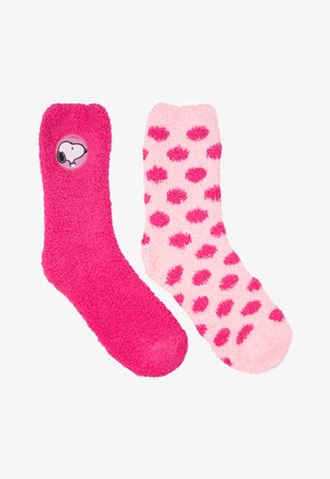 Set mit kuscheligen Socken, bestehend aus einer einfarbigen, leuchtend rosa Socke mit einem Snoopy-Motiv und einer hellrosa Socke mit dunkelpinkfarbenen Punkten.