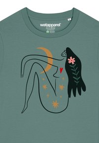 Groene t-shirt met een lijntekening van een leunend figuur met een halve maan, sterren, een bloem en bladaccenten in oranje en donkergroen.