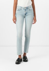 Lichtblauwe jeans met rechte pijpen van denim met een vervaagde was, met vijf zakken en een knoopsluiting. Draag met zwarte instappers.