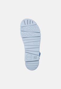 Light blue rubber shoe sole with textured patterns, including horizontal lines and wave shapes, and embossed brand logo and size.