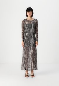 Dolga obleka z vzorcem kače v odtenkih sive in rjave. Prozoren, lahkoten material seže do gležnjev, v kombinaciji s črnimi sandali.