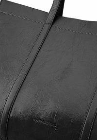 Borsa tote in pelle nera con texture stropicciata, cuciture a punto singolo e due manici piatti. Presenta il nome del brand in rilievo sul lato.