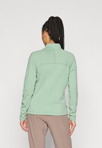 Φωτεινό πράσινο πουλόβερ με ψηλό γιακά, υφασμάτινη υφή και μακριά μανίκια. Διαθέτει λεπτομέρεια ραφής στην άνω πλάτη.