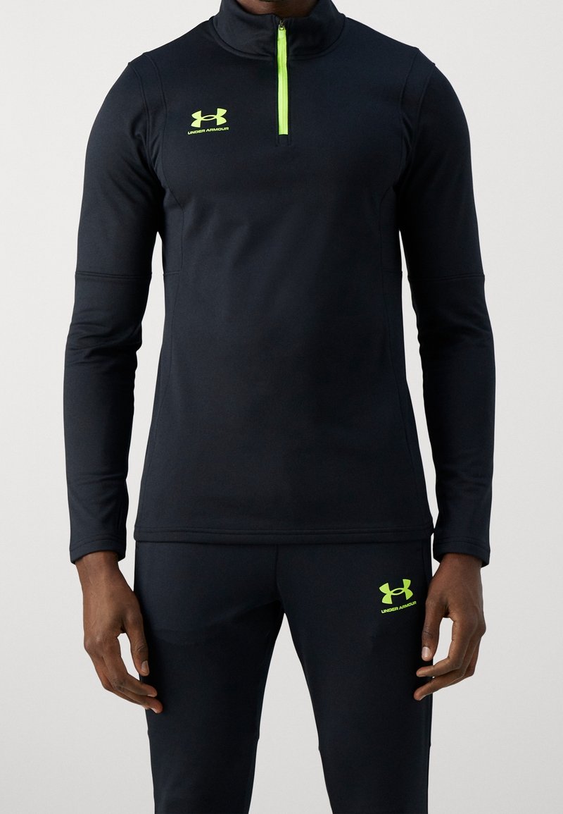 Svart långärmad sporttröja med halvdrajust, med en neongrön dragkedja och logotyp. Slät tyg med en figurnära design, kombinerad med matchande byxor.