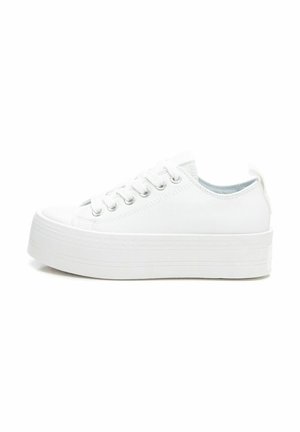Zapatillas de lona blancas con suela de goma blanca gruesa, puntera redondeada, seis ojales metálicos y una lengüeta en el talón para facilitar el uso.