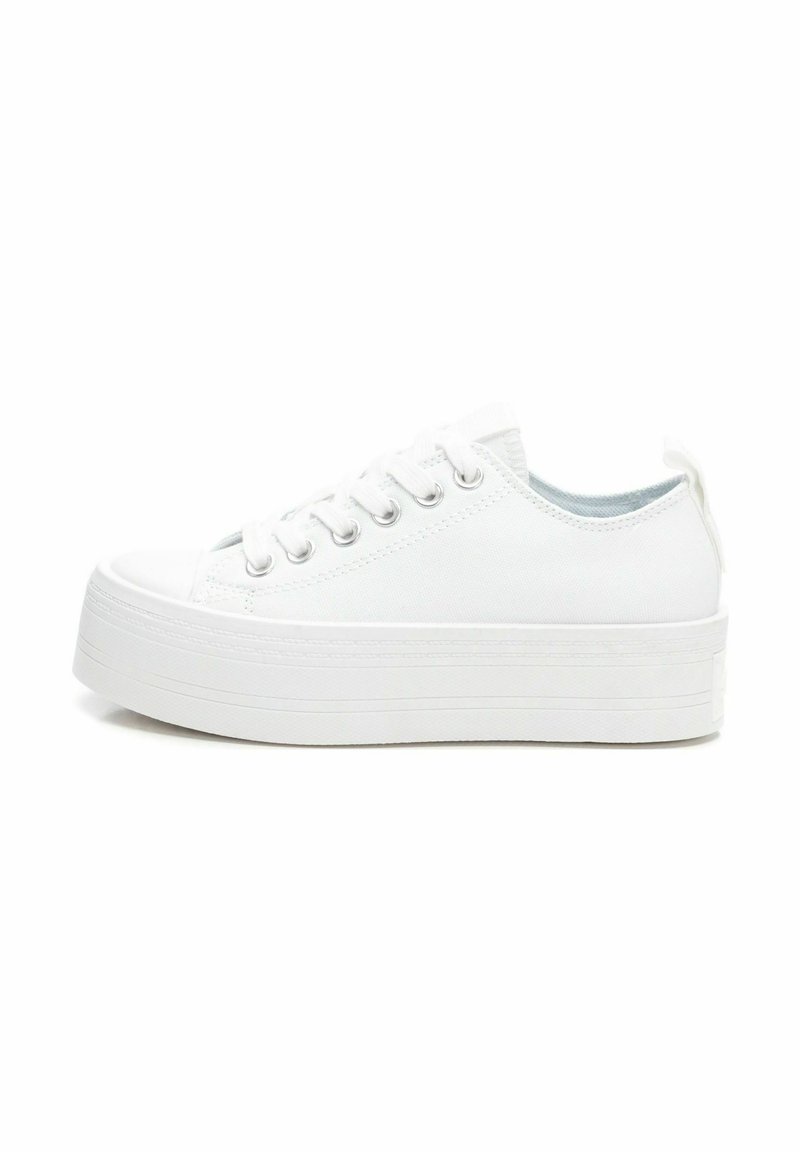 Zapatillas de lona blancas con suela de goma blanca gruesa, puntera redondeada, seis ojales metálicos y una lengüeta en el talón para facilitar el uso.