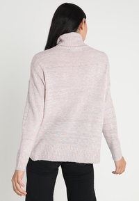 Hellrosa, gemütlicher Rollkragenpullover mit strukturierter Strickoptik und dezenten mehrfarbigen Sprenkeln; oversized Passform mit gerippten Bündchen und Saum.