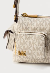 Τσάντα χειρός από μπεζ υφασμα με υφή, που φέρει ένα έντονο λογότυπο MK, θήκες με φερμουάρ και διακοσμητικά σε χρυσό τόνο.