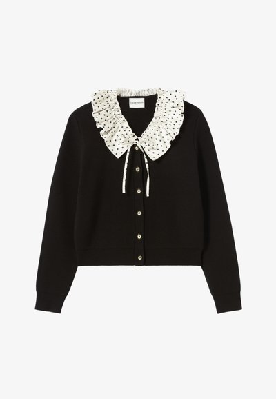 Cardigan noir avec un col froncé à pois blancs, fermeture par boutons à l'avant et poignets côtelés. Texture douce, design ajusté, look classique.