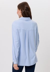 Losvallend model, blauw-wit gestreept overhemd met lange mouwen, een kraag, knoopmanchetten en een plooi aan de achterkant. Zachte stof, gladde textuur.