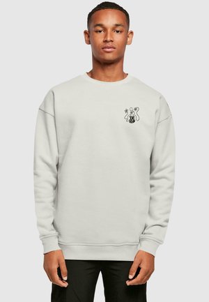 Lysegrå sweatshirt lavet af blødt stof, har rund hals, afslappet pasform og et sort grafisk design på brystet.