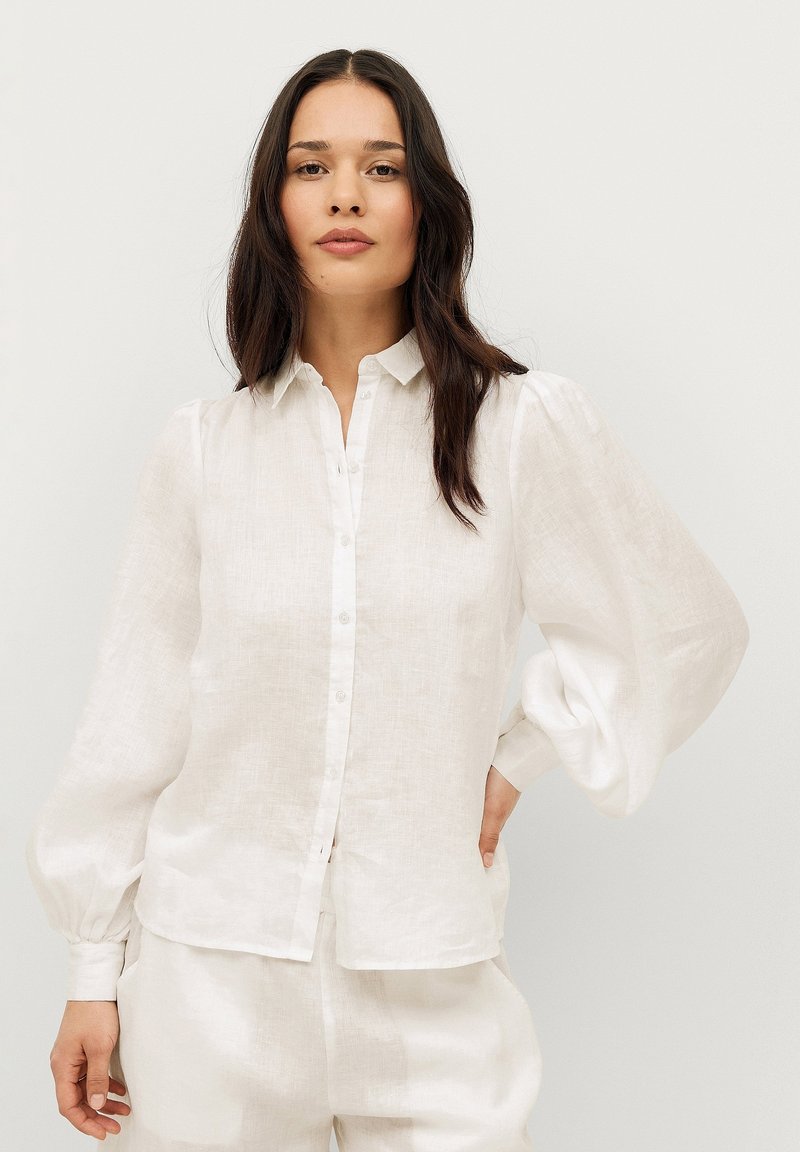 Witte linnen blouse met een knoopsluiting aan de voorkant, pofmouwen en een klassieke kraag, gemaakt van een lichtgewicht, textuurstof voor ademend vermogen.